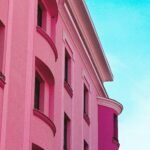 A stunning pink building facade against a bright blue sky in Timisoara, Romania.